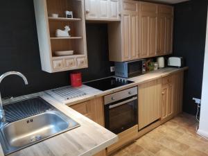 una cocina con armarios de madera y fregadero en Blair Drummond Holiday Home, en Doune