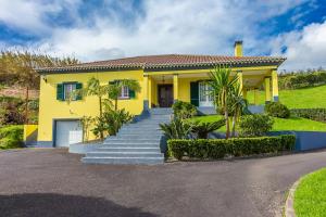 a yellow house with stairs in front of it at Quinta das Palmeiras in Povoação