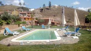 a pool with chairs and umbrellas in a yard at Refúgio do Raposo/CASA Altair in Montes da Senhora