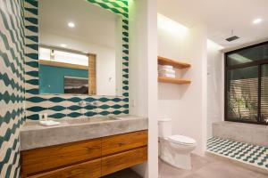 ein Badezimmer mit einem Waschbecken, einem WC und einem Spiegel in der Unterkunft The Gilded Iguana in Nosara