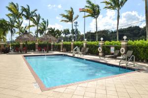 una piscina en un complejo con sillas y palmeras en Holiday Inn Express & Suites Florida City-Gateway To Keys, an IHG Hotel, en Florida City