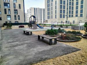 a park with benches and a playground with tall buildings at apartamento La Coqueta in Santander