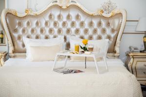 ein weißes Bett mit einem weißen Tisch und einem Tablett mit Essen in der Unterkunft De Versal in Odessa