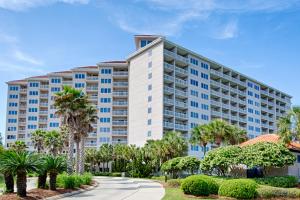 a large apartment building with palm trees and a sidewalk at TOPS'L Summit VI in Destin
