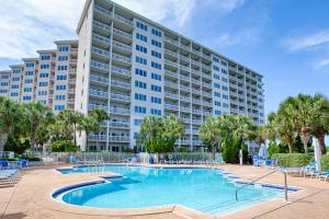 a large apartment building with a swimming pool and palm trees at TOPS'L Summit VI in Destin