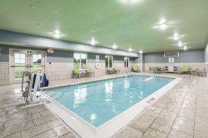einen großen Pool in einem Fitnessraum mit Tischen und Stühlen in der Unterkunft Holiday Inn Express Hotel & Suites Jasper, an IHG Hotel in Jasper