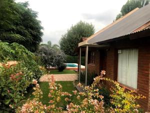 una casa con un jardín con flores delante en Casa Loft Rumipal en Villa Rumipal