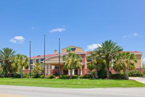 a building with palm trees in front of a street at Holiday Inn Express & Suites Wharton, an IHG Hotel in Wharton