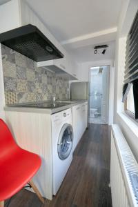 a kitchen with a washing machine and a red chair at Stanford Guesthouse in Bucharest