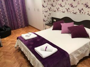 Apartamento turístico iguazu في ريباديو: غرفة نوم مع سرير ومناشف أرجوانية وبيضاء