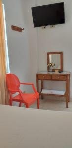 una camera con scrivania, sedia rossa e specchio di Hotel Comercial Neiva a Neiva