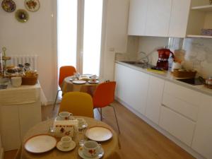 une cuisine avec une table, des chaises et une petite table avec des tasses dans l'établissement Il Cantico B&B, à Capurso