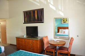Habitación de hotel con escritorio, TV y espejo. en Howard Johnson by Wyndham Yuma, en Yuma