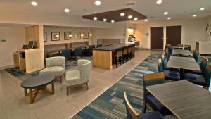 a dining room with tables and chairs and a bar at Holiday Inn Express & Suites Evansville North, an IHG Hotel in Warrenton