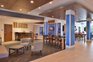 a lobby with tables and chairs and a bar at Holiday Inn Express & Suites Omaha Airport, an IHG Hotel in Carter Lake