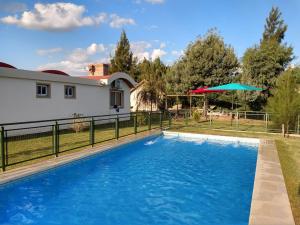 a swimming pool with a fence and a house at Cabañas Elabu in San Miguel del Monte