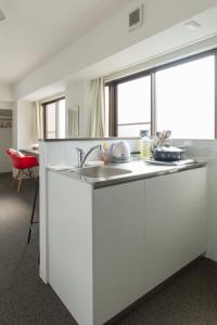 a white kitchen with a sink and a window at BEEHIVE APARTMENT Moriguchi in Osaka
