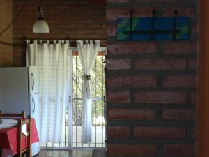 una pared de ladrillo con una ventana con cortinas blancas en Cabañas Valentina en Cortaderas