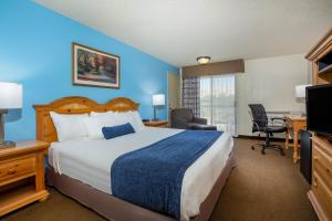 a hotel room with a large bed and a desk at Baymont by Wyndham Yakima Riverfront in Yakima
