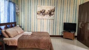 a bedroom with a bed and a flat screen tv at Carlo'S Place in Dumaguete