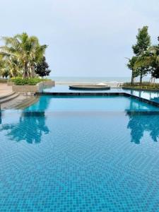 a large swimming pool with blue water and palm trees at kuantan staycationtimurbay in Kuantan
