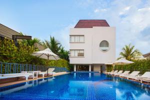 a pool with chairs and umbrellas next to a building at Damrei Angkor Hotel in Siem Reap