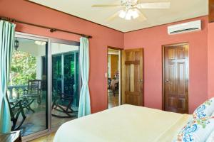 um quarto com paredes cor-de-rosa e uma cama com uma ventoinha de tecto em Villas Iguana A-2 Beachfront Condo em Rivas