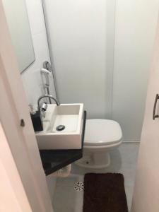 La salle de bains blanche est pourvue d'un lavabo et de toilettes. dans l'établissement apartamento próximo a praia da Enseada, à Guarujá