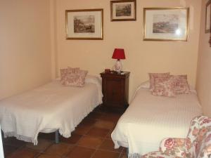 um quarto com duas camas, um candeeiro e uma cadeira em Las Cañadillas em El Castillo de las Guardas