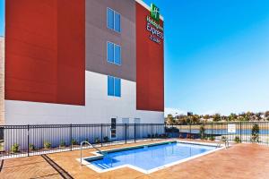 a hotel with a swimming pool in front of a building at Holiday Inn Express & Suites Tulsa West - Sand Springs, an IHG Hotel in Sand Springs