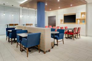 uma sala de jantar com mesas e cadeiras e uma televisão de ecrã plano em Holiday Inn Express & Suites - King George - Dahlgren, an IHG Hotel em Alden