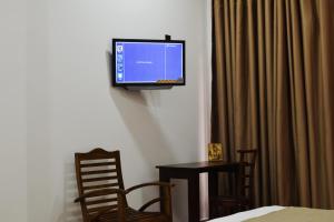 Monarch Residence في بولوناروا: تلفزيون بشاشة مسطحة على جدار مع طاولة وكراسي