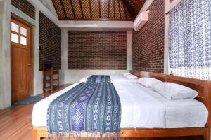 a bedroom with a large bed with a brick wall at Saka Homestay Boutique & Cafe in Borobudur
