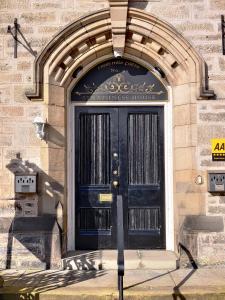 uma porta preta no lado de um edifício em Strathness House em Inverness