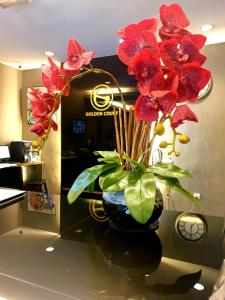 a vase filled with red flowers on a counter at Golden Court Hotel - Tun Abdul Razak in Johor Bahru