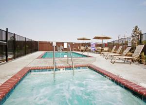 a swimming pool with chairs and an umbrella at Holiday Inn Express & Suites Dinuba West, an IHG Hotel in Dinuba