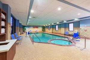 una piscina en una habitación de hospital con sillas azules en Holiday Inn Express & Suites Houston - Memorial Park Area, an IHG Hotel en Houston