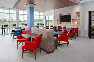 uma sala de espera com mesas e cadeiras e uma televisão de ecrã plano em Holiday Inn Express & Suites - Elkhorn - Lake Geneva Area, an IHG Hotel em Elkhorn