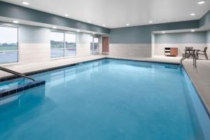 Holiday Inn Express & Suites - Elkhorn - Lake Geneva Area, an IHG Hotel في Elkhorn: حمام سباحة بمياه زرقاء في غرفة في الفندق