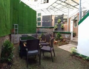 eine Terrasse mit einem Tisch und Stühlen sowie einer grünen Wand in der Unterkunft 3BU Hostel Baguio - Session-Governor Pack in Baguio City
