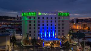 チワワにあるHoliday Inn Express & Suites Chihuahua Juventud, an IHG Hotelの青と緑の灯りが灯る建物