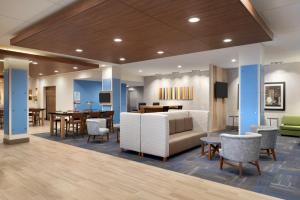 a lobby with a waiting area with tables and chairs at Holiday Inn Express & Suites - Cincinnati South - Wilder, an IHG Hotel in Wilder