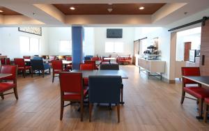 een eetkamer met tafels en rode stoelen bij Holiday Inn Express Hotel & Suites Cincinnati Southeast Newport, an IHG Hotel in Bellevue