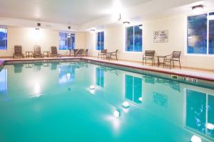 een zwembad met stoelen en tafels bij Holiday Inn Express Hotel & Suites Cincinnati Southeast Newport, an IHG Hotel in Bellevue
