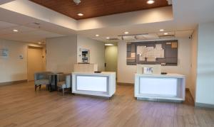 a waiting area in a hospital with chairs and a table at Holiday Inn Express Hotel & Suites Cincinnati Southeast Newport by IHG in Bellevue
