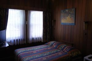 a small bedroom with a bed and two windows at Moruya Monarch Hotel in Moruya