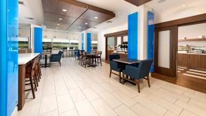 a dining room with tables and chairs and a kitchen at Holiday Inn Express Hotel and Suites Conroe by IHG in Conroe