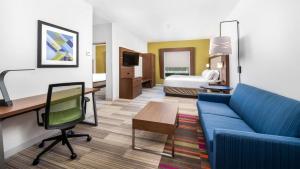 a hotel room with a blue couch and a bed at Holiday Inn Express Hotel and Suites Conroe by IHG in Conroe