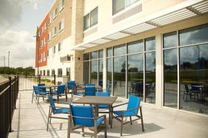 un patio avec des tables et des chaises en face d'un bâtiment dans l'établissement Holiday Inn Express & Suites - Kansas City - Lee's Summit, an IHG Hotel, à Lee's Summit