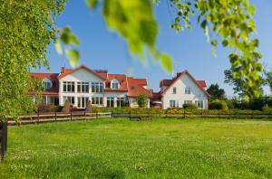 a large house with a fence and green grass at Pensjonat nad Płaskim in Jerzwałd